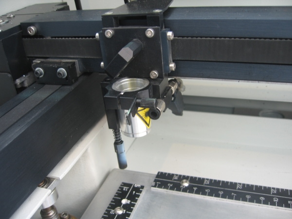 Image of a black laser engraving machine getting ready to engrave a plastic material