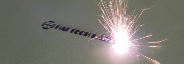 Image of a laser marking a piece of metal with the Hai Tech Laser's logo